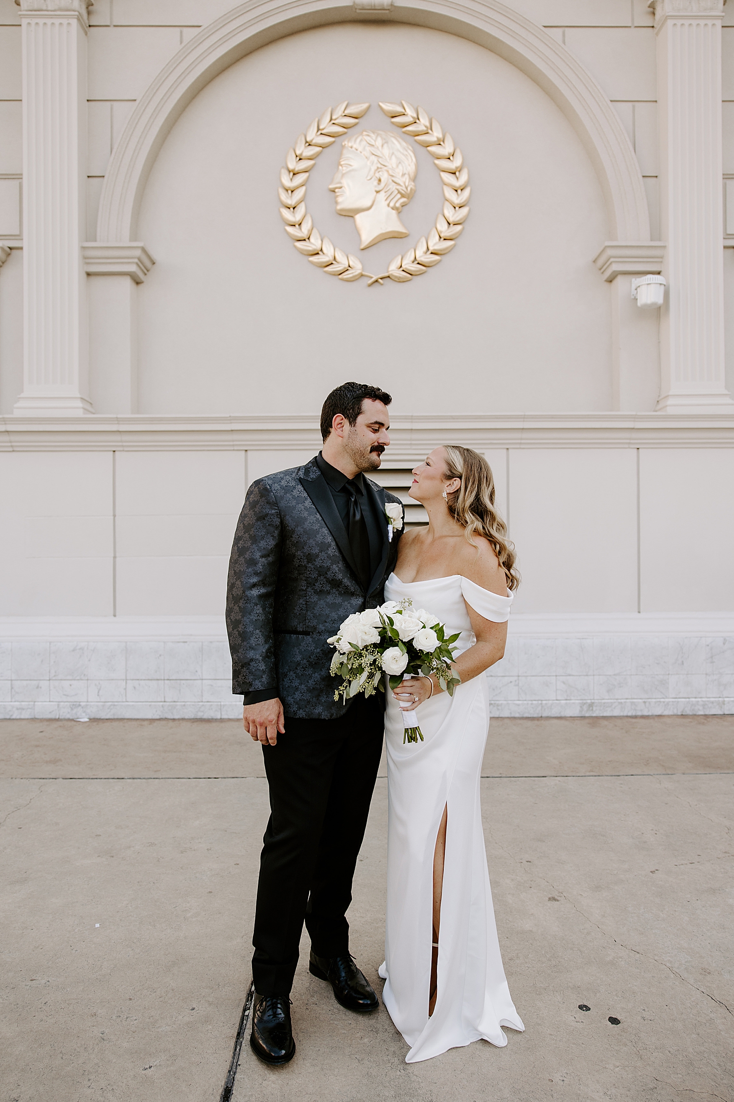 newlyweds stand under Caesar's palace logo by Katelyn Faye Photography