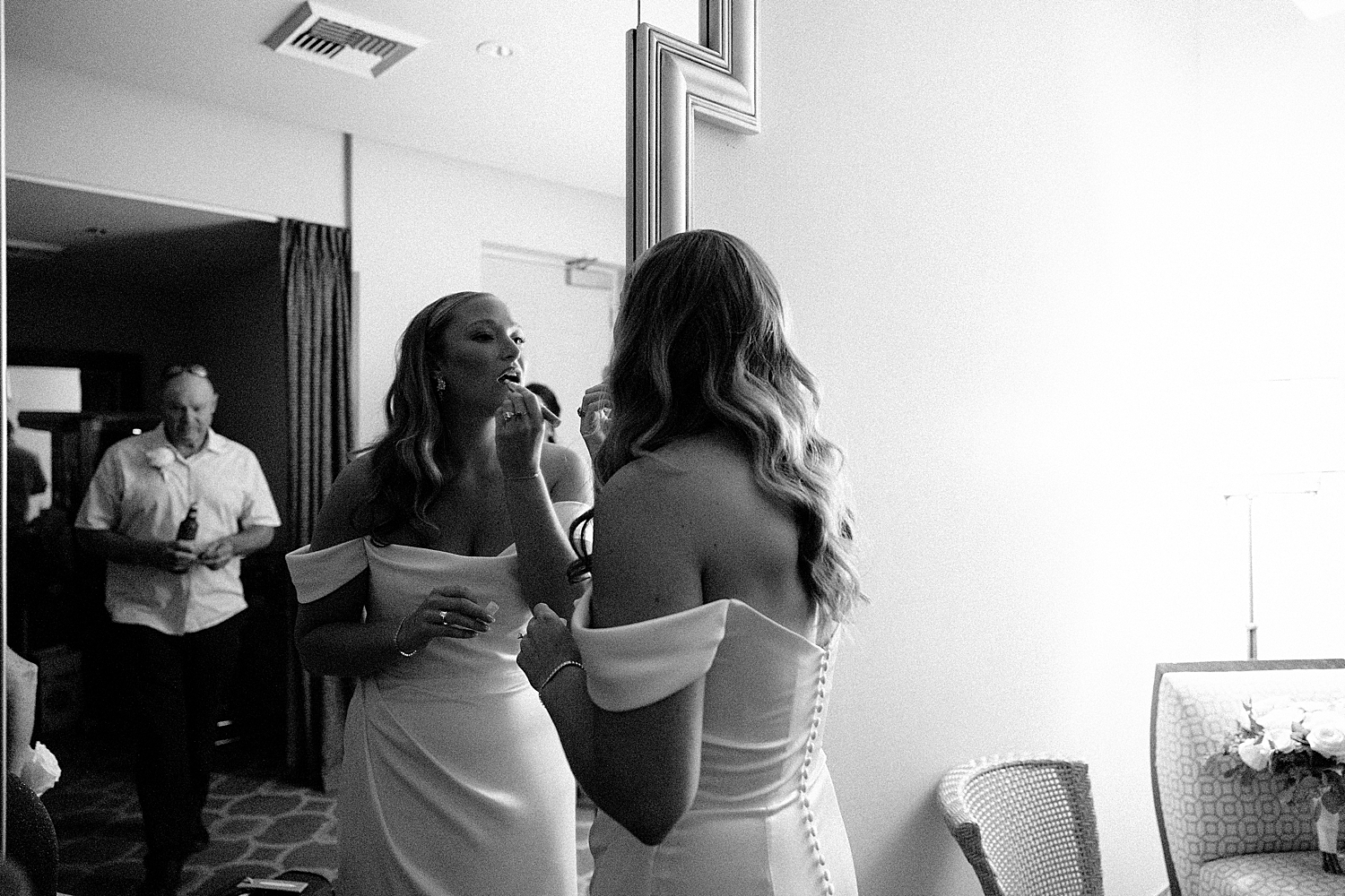 bride puts on her lipstick in the mirror at Juno Garden