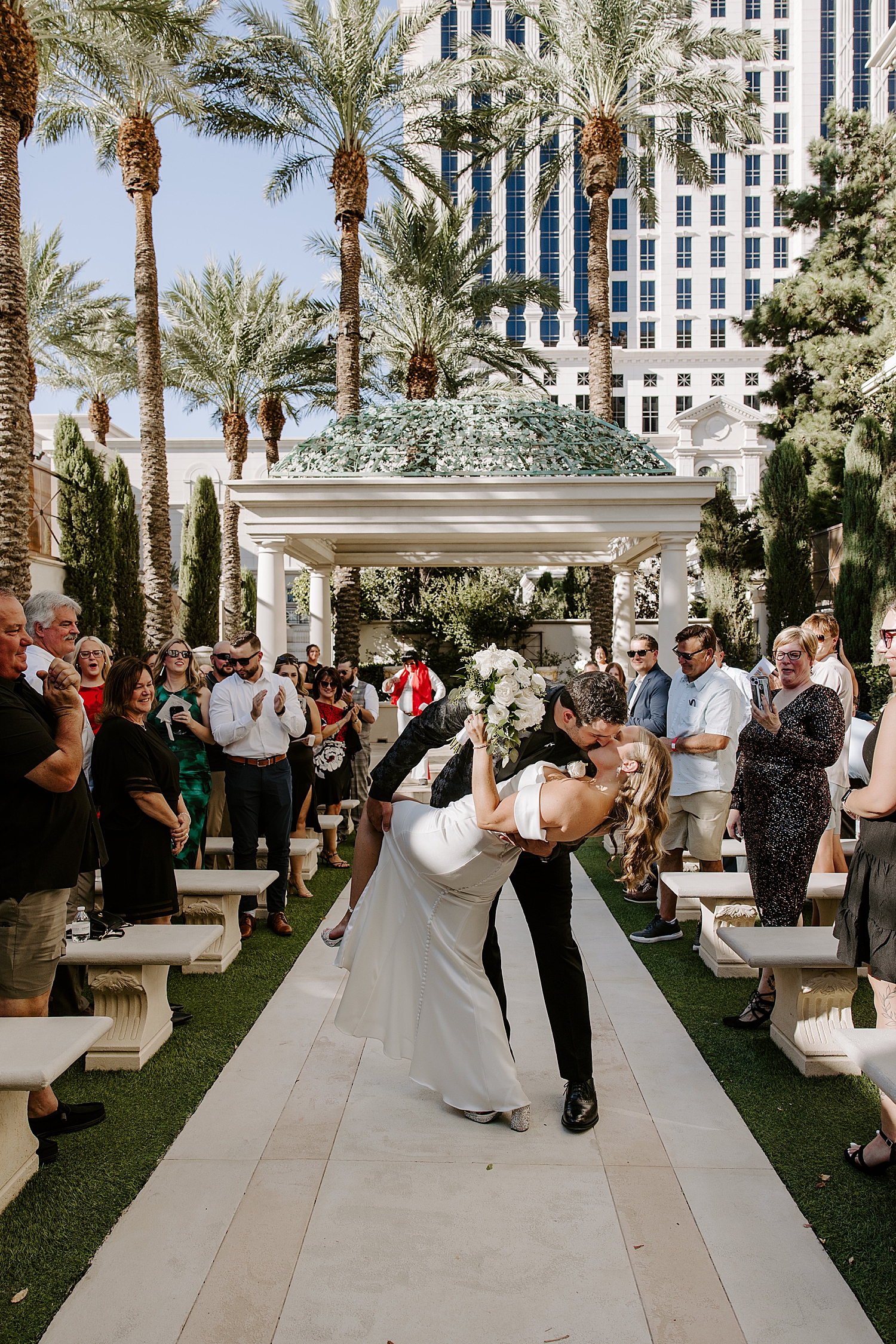 groom dips bride for kiss in at end of aisle in Juno Garden