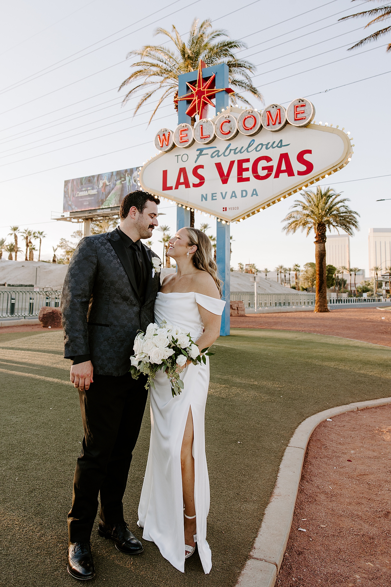 newlyweds embrace under neon sign after ceremony in Juno Garden