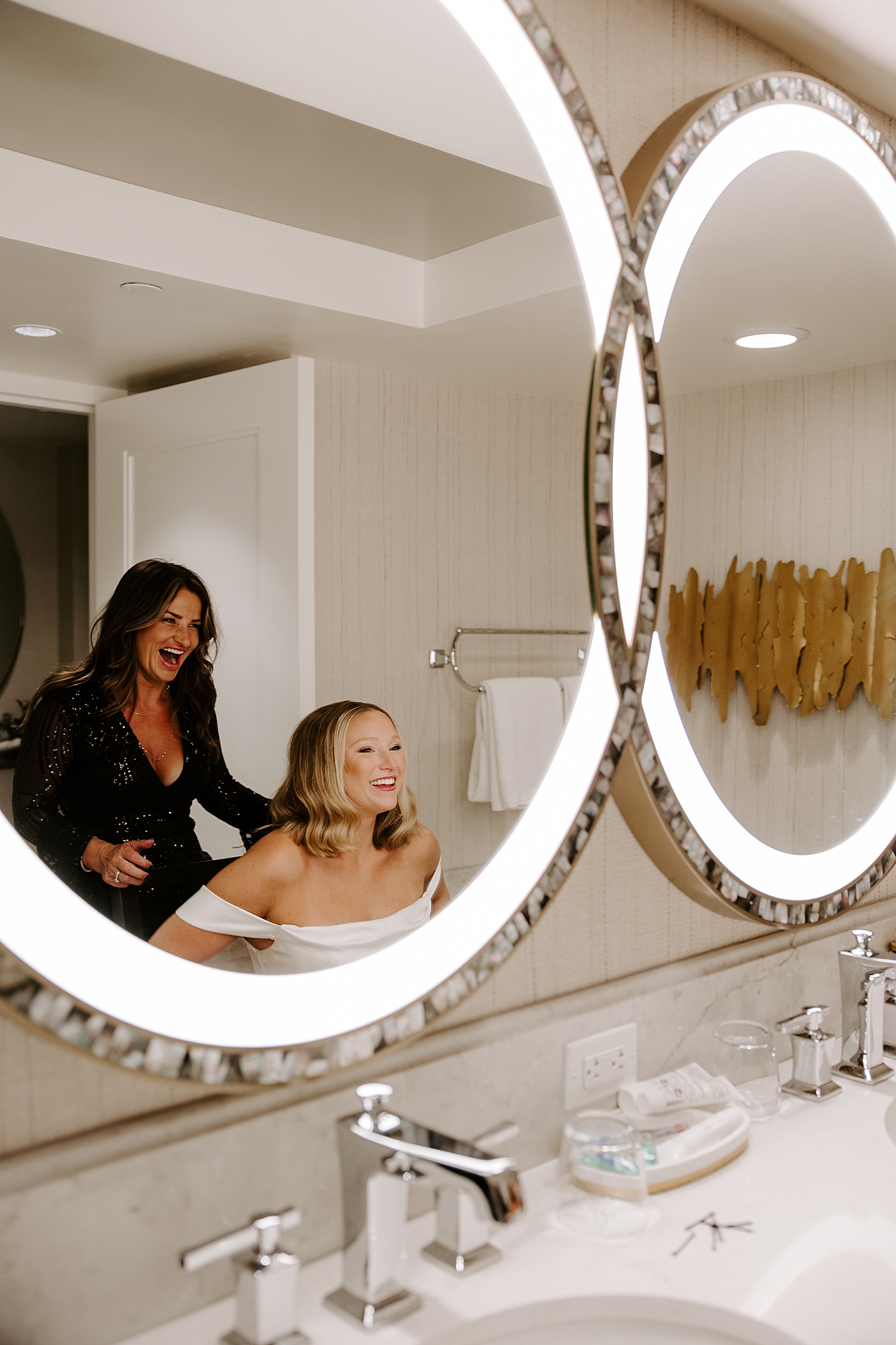woman smiles in the mirror at her post-ceremony hair chop by Las Vegas wedding photographer