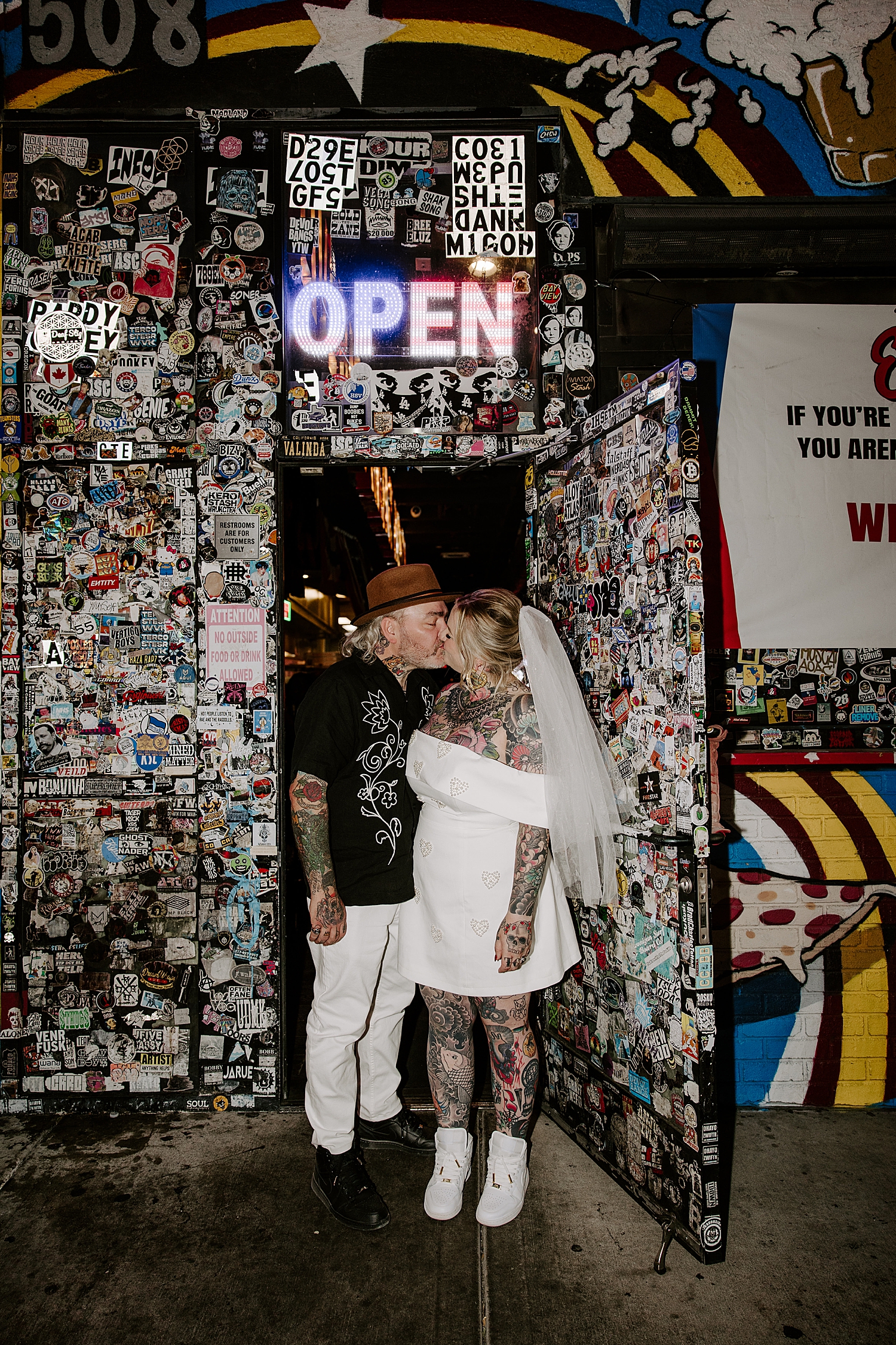 bride and groom share a kiss under sticker wall by Katelyn Faye Photography