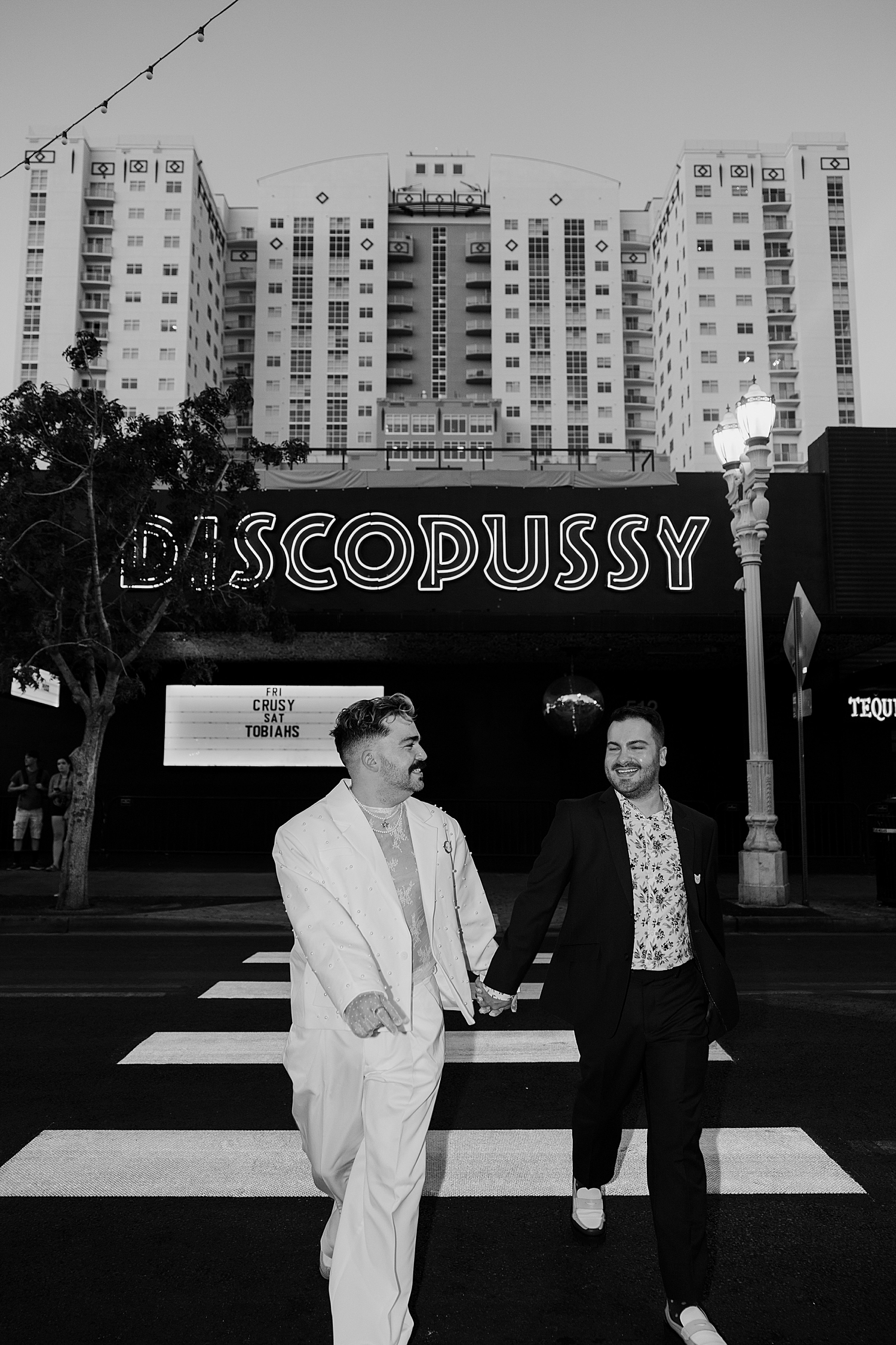 two men walk across crosswalk hand in hand by Katelyn Faye Photo