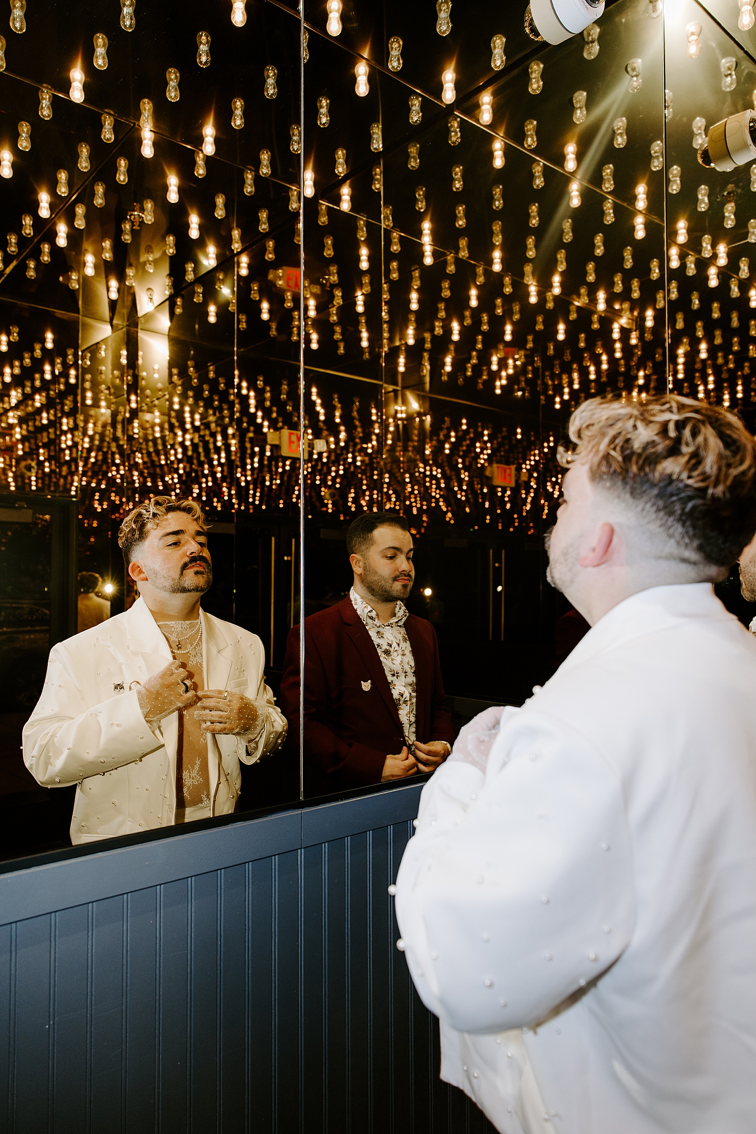 newlyweds in fancy suits adjust blazers in mirror by Katelyn Faye Photo