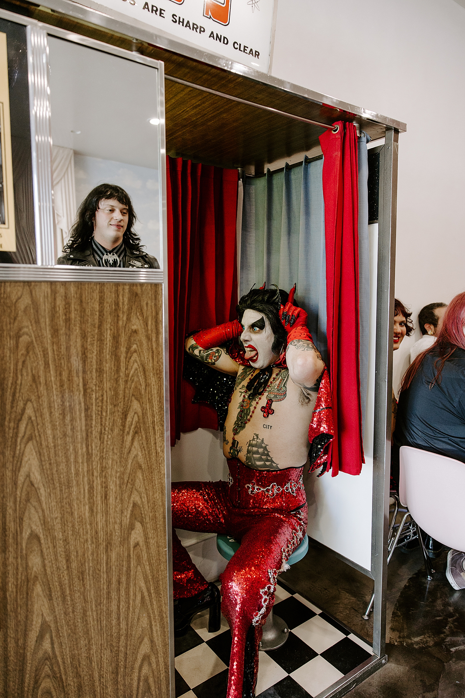man in costume sits in photo booth for elopement with Hellvis