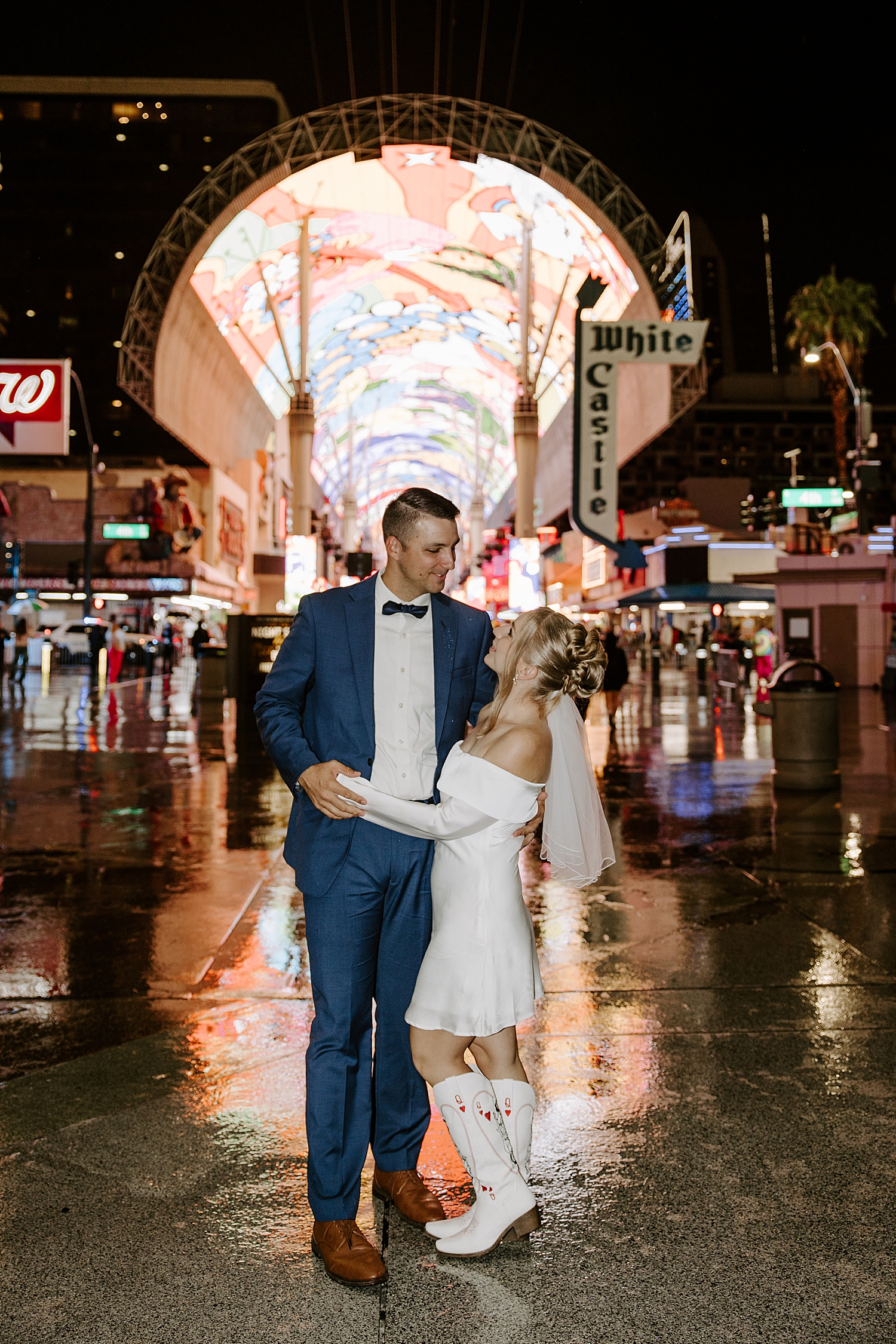 husband and wife stand in crowded fremont street for rainy elopement