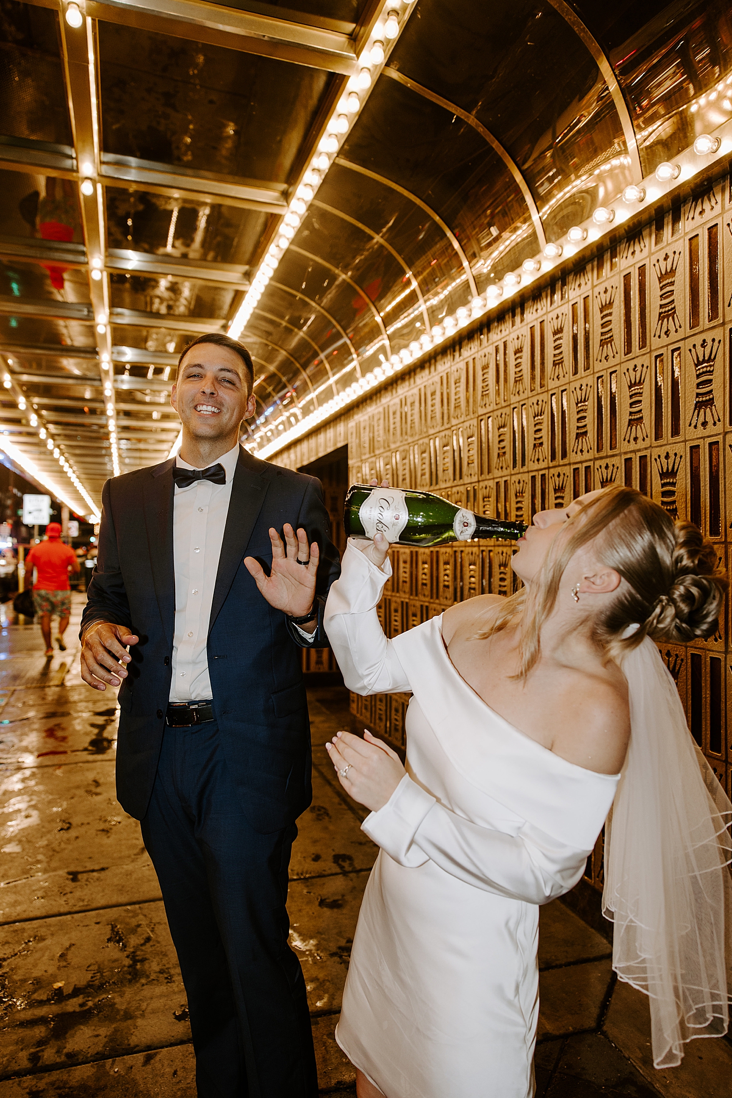 bride drinks champagne out of bottle under street lights by Las Vegas Wedding Photographer