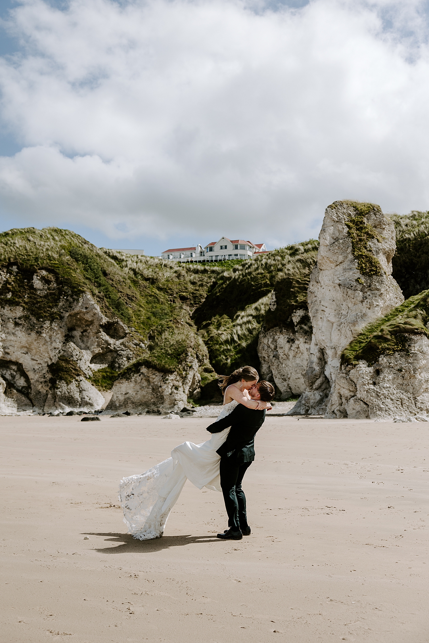 man lifts up his wife on beach by Katelyn Faye Photo