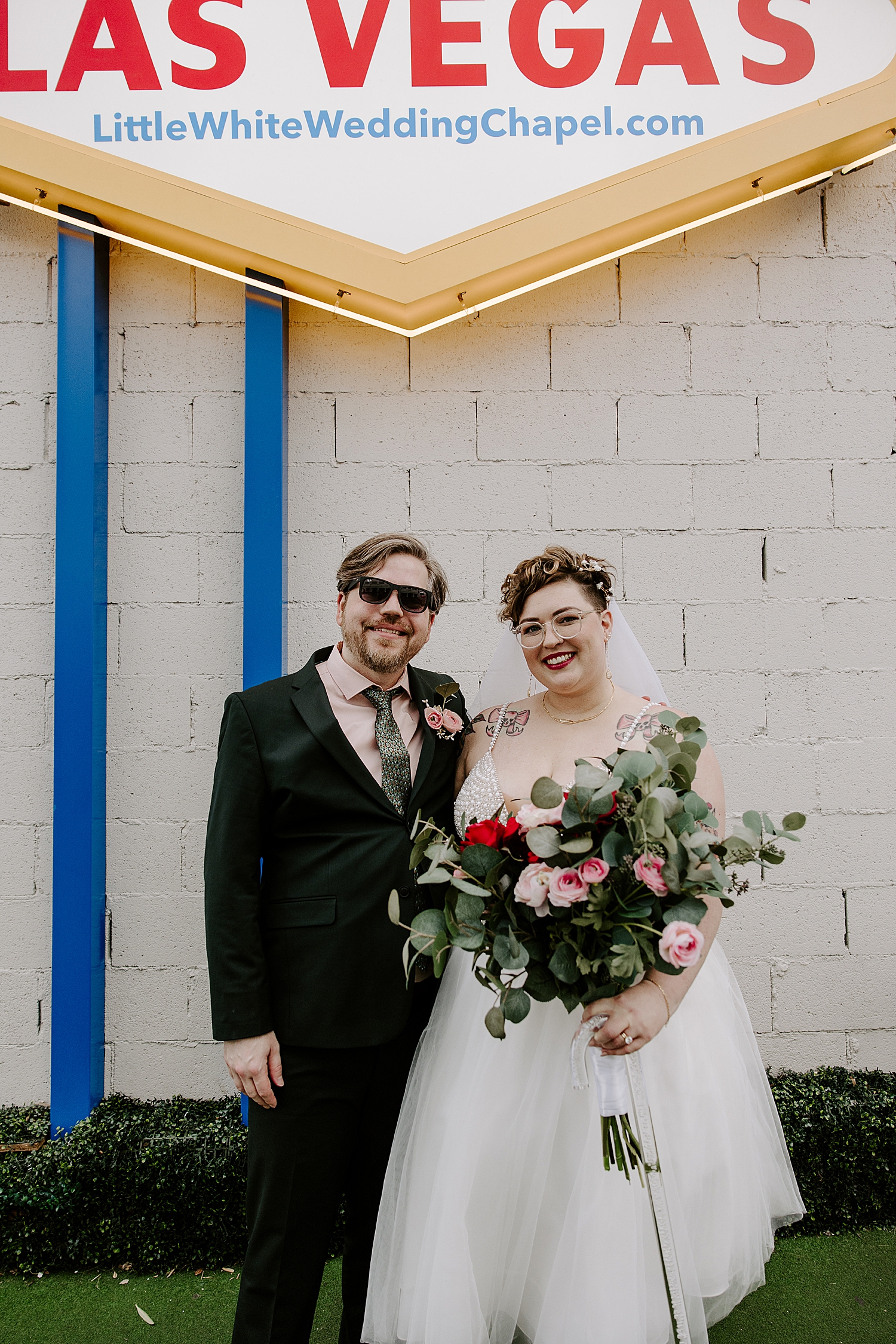 bride and groom stand in front of bright sign for sentimental LWC elopement