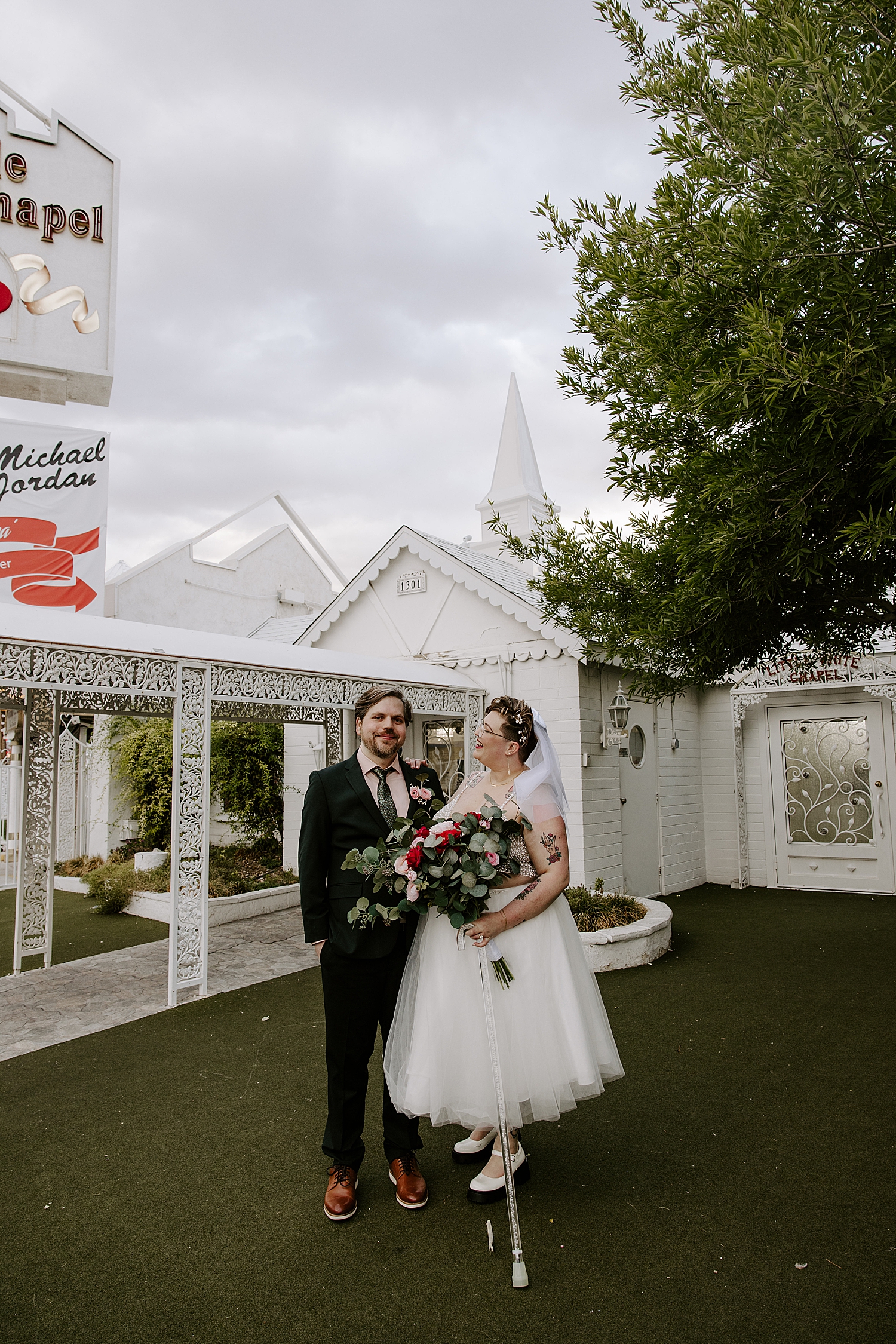 woman in short white tulle dress with man in suit in front of white building for sentimental LWC elopement