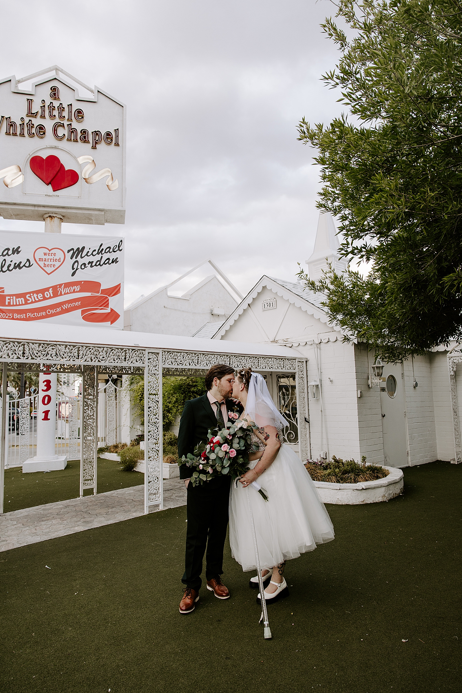 newlyweds kiss in front of white buildling by Las Vegas wedding photographer