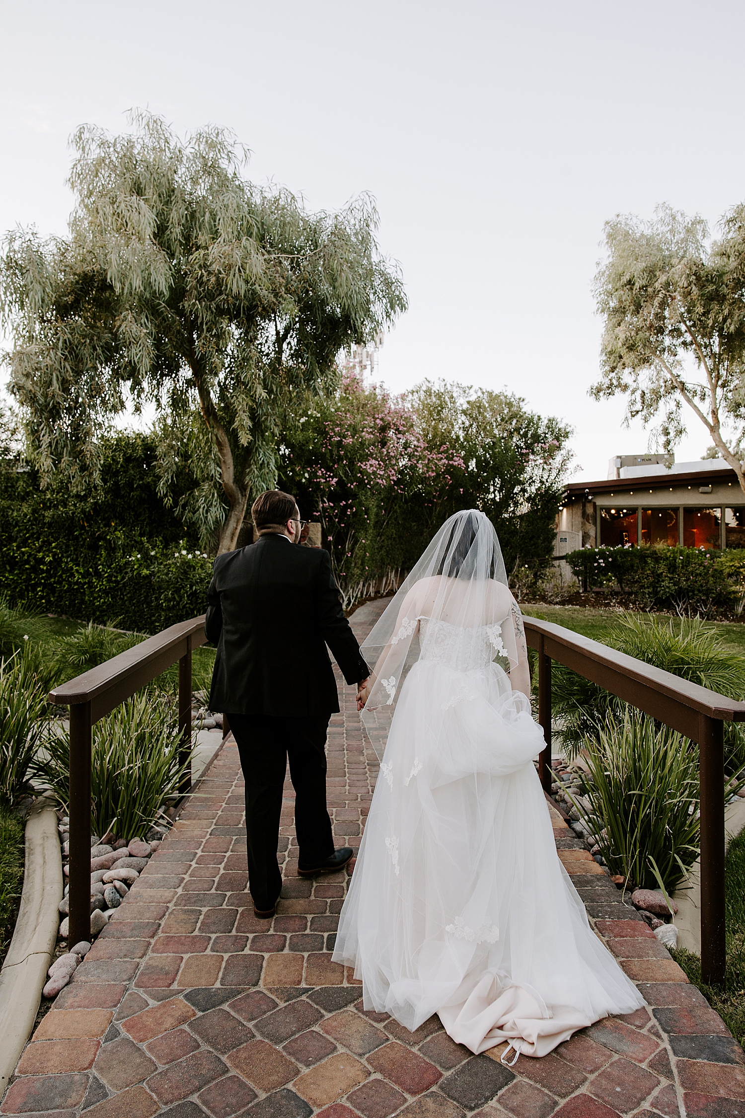 husband and wife walk across bridge together by Katelyn Faye Photography