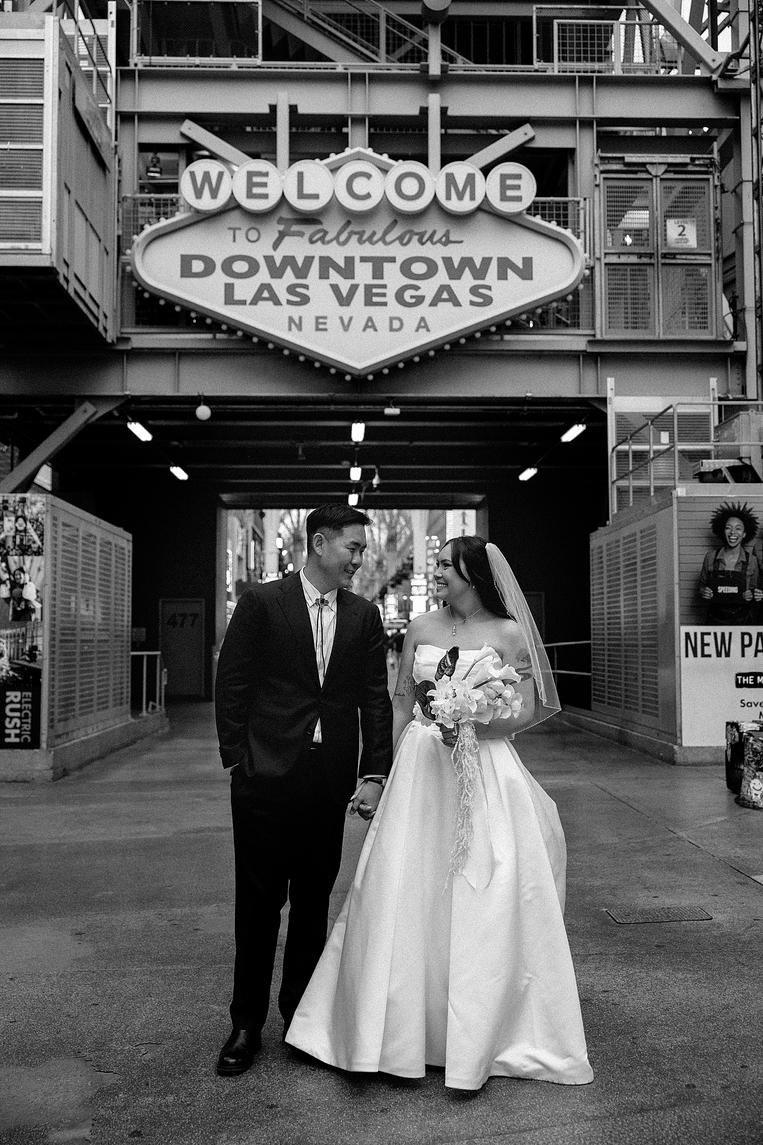 newlyweds stand under neon sign before fun-filled celebration