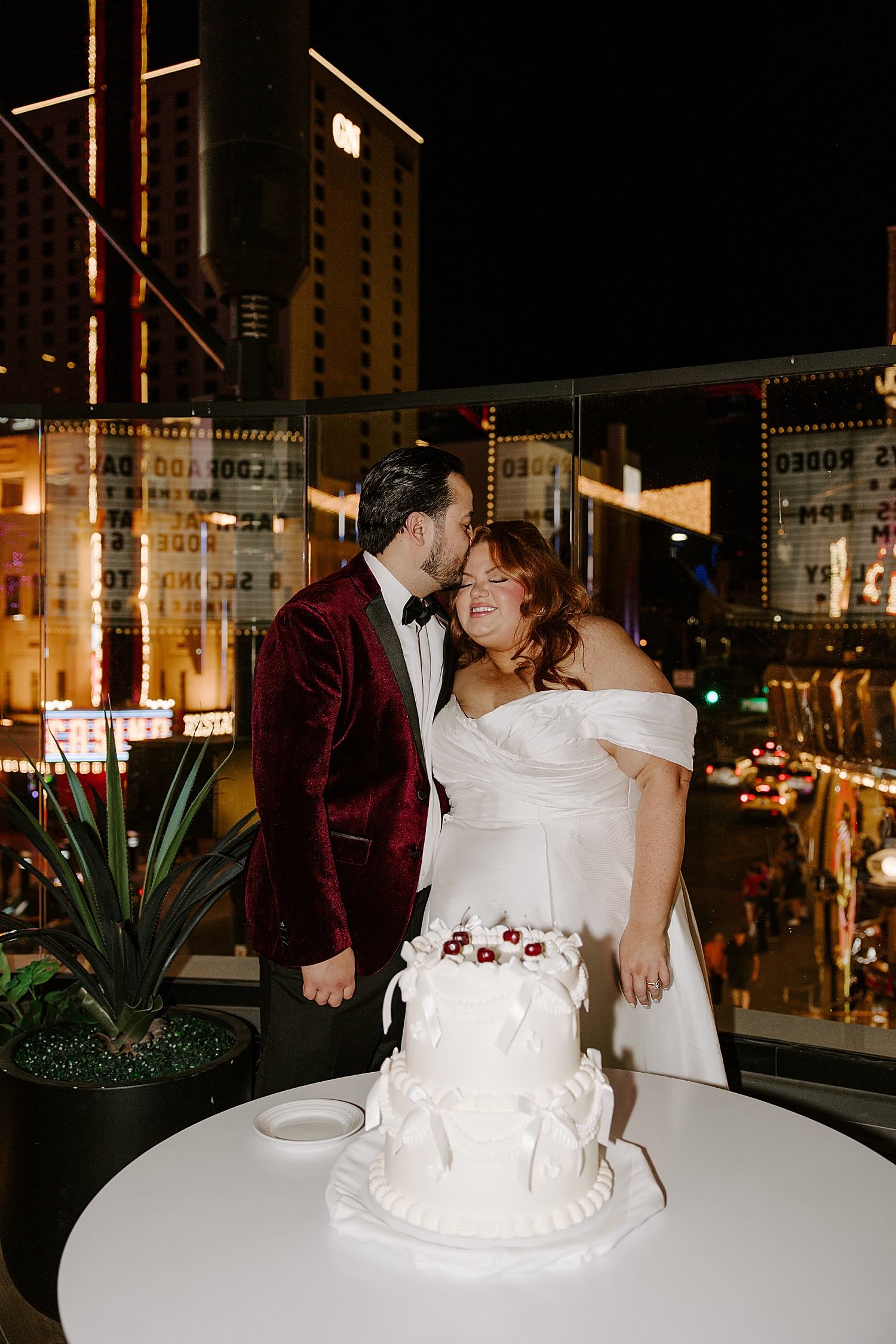 newlyweds share a kiss behind two teir cake on outdoor patio by LV Wedding photographer