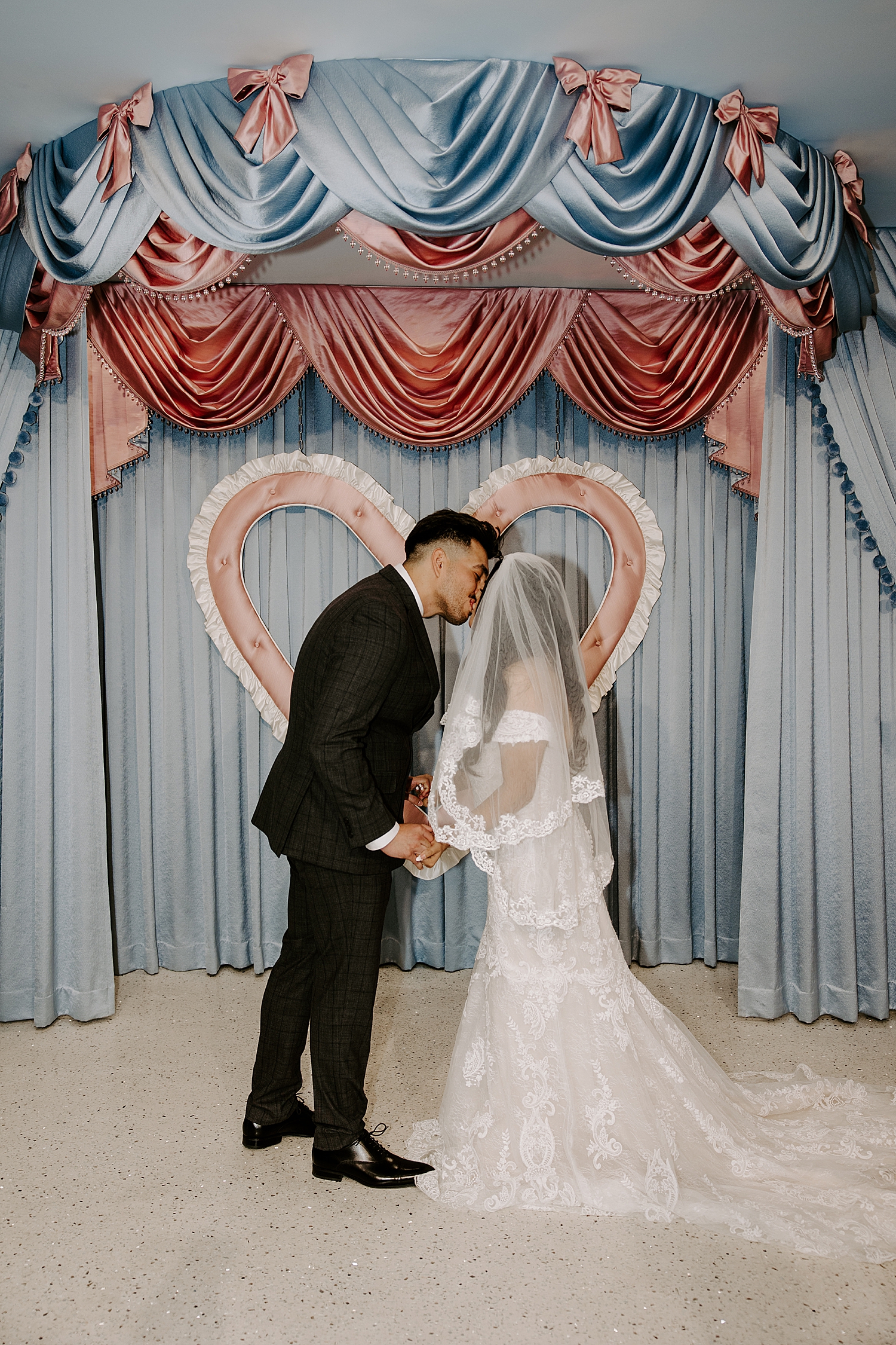 newlyweds share a kiss at alter in front of blue curtains by Las Vegas elopement photographer