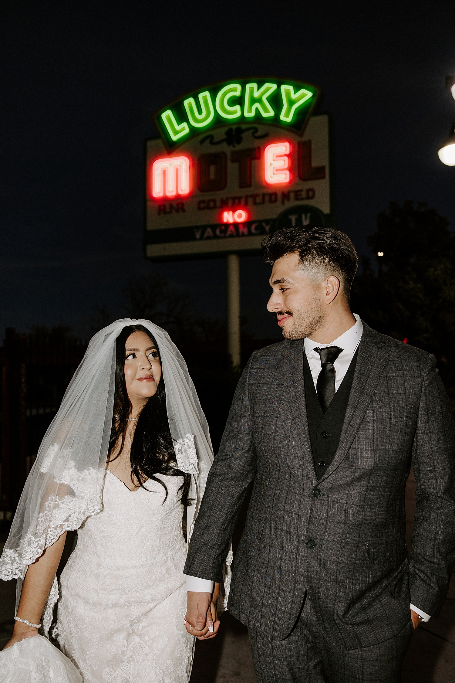 couple walks down street with neon lights at their vintage aesthetic wedding