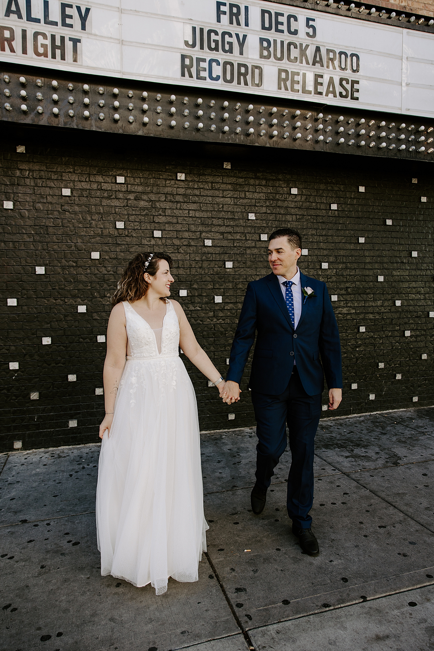 newlyweds walk hand in hand down sidewalk for Fremont Street elopement portraits