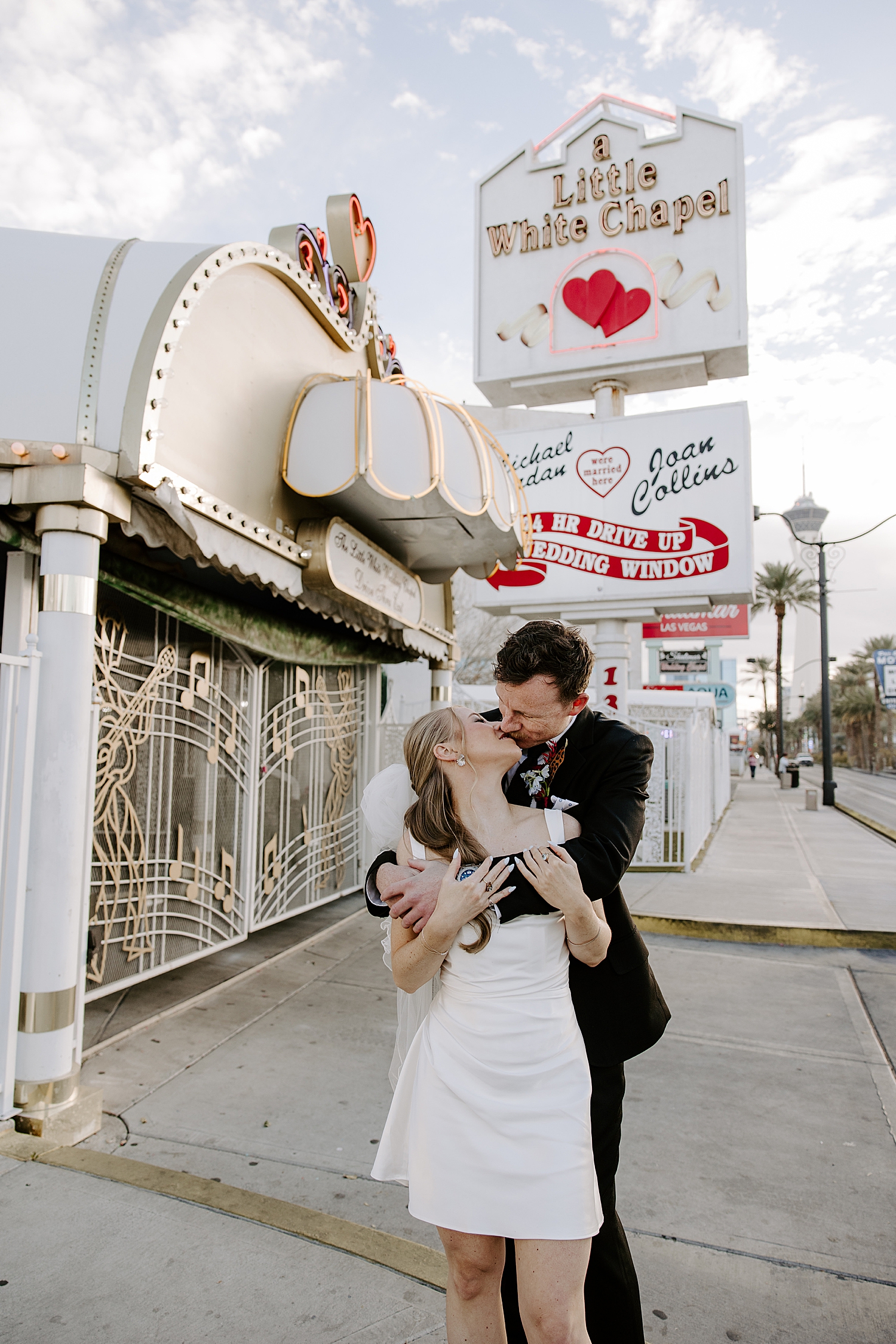 couple kiss in front of iconic sign after figuring out how to get married at a little white chapel